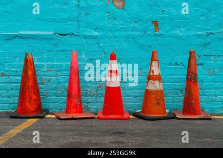 Lined up orange cones with blue painted brick wall in the background. Stock Photo