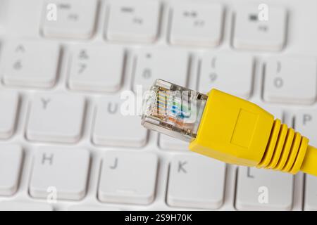 Ethernet cable and computer keyboard. LAN network, data transfer speed and internet connection concept. Stock Photo