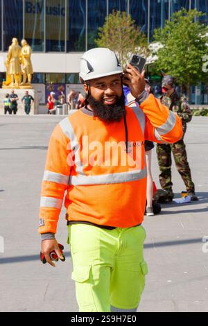 smiling asian construction worker on mobile phone at Birmingham Pride celebrating LGBT+ diversity and equality Stock Photo