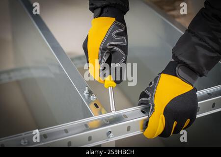 Worker hands in safety gloves mounting modular steel components with using screwdriver Stock Photo