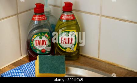 Sharp focus on two bottle of Fairy washing up liquid with an out of focus sponge and dish cloth in the foreground Stock Photo