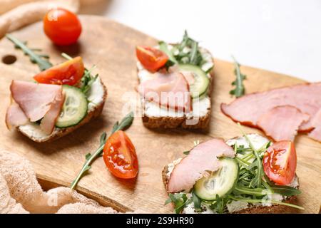 Wooden board of delicious sandwiches with cream cheese, ham and vegetables, closeup Stock Photo