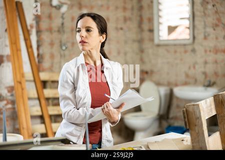 Interested brunette making notes while planning home renovation Stock Photo