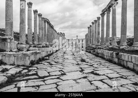 A long, narrow street with a lot of pillars. The pillars are old and worn, and the street is empty. Scene is somber and quiet Stock Photo