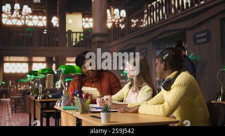 Teacher assisting scholars with class homework for mentoring session, providing academic instruction and support to help with the curriculum. Tutor lecturer gives private lessons. Camera A. Stock Photo