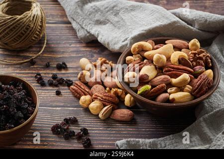 Mix of Various Nuts and Raisins in a Wooden Bowl on a Gray Cloth on a Wooden Table Stock Photo
