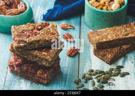 Energy Bars and Mix nuts on a Blue Color Wooden Table. Walnuts, Peanuts, Pecan, Almonds, Cashews, Pistachio Stock Photo