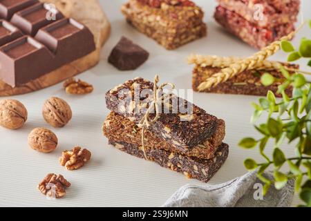 Energy Bars with Chocolate and Mix nuts on a White Table. Walnuts, Peanuts, Pecan, Almonds, Cashews, Pistachio Stock Photo