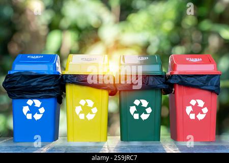 A row of trash cans are lined up in a row, with each one a different color. Collection of waste bins full of different types of garbage, recycling and Stock Photo