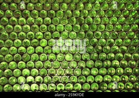 Full frame wall with empty green beer bottles bottoms. Alcohol theme. Endless rows of wine bottles. Green glass bottle wall with sunlight from behind Stock Photo