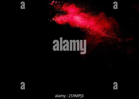 Red dust particles explosioon on black background.Red powder splash. Stock Photo