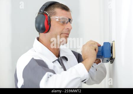 male builder using sander on plasterboard wall Stock Photo