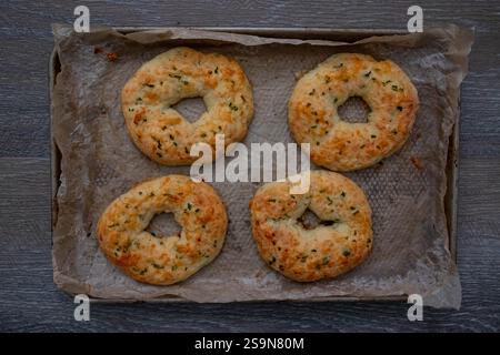 Cooked four homemade jalapeno cheese bagels, parchment paper on wood. Stock Photo