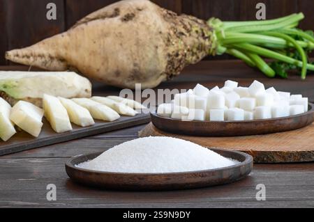 Granulated and cube sugar in bowl with fresh raw sugar beetroot on wooden table, beta vulgaris Stock Photo