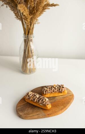 Hazelnut cream eclairs on wooden train against white background Stock Photo