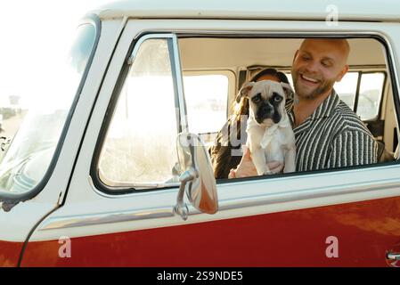 Puppy passenger enjoying golden hour vibes with their happy humans Stock Photo
