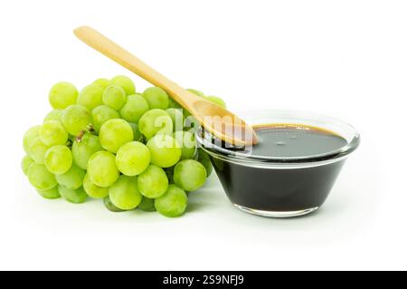 Bunch of fresh green grape and grape molasses in glass bowl isolated on white background, clipping path. Food sauce concept Stock Photo