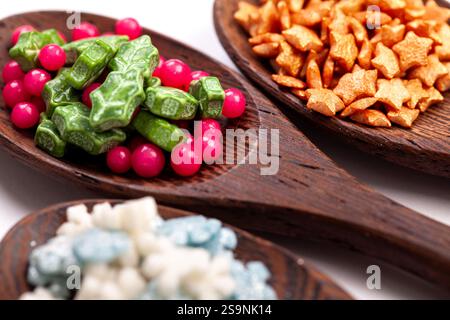 Three wooden spoons with christmas cake sprinkles on isolated on a white background. Stock Photo