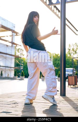 Young dancer showcases contemporary hip-hop style in urban setting during sunset Stock Photo