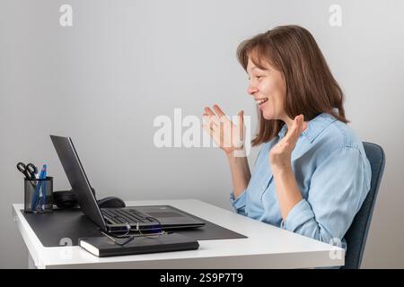 Happy young woman using laptop, watching webinar, studying online, looking at pc screen learning web classes or having virtual call meeting remote wor Stock Photo