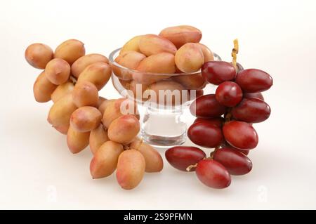 Fruits, two red on pink dates Bouquet held in cup on white background Stock Photo
