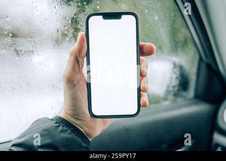 Smartphone mockup screen, male driver using mobile phone in car on cold winter day, selective focus Stock Photo