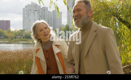Happy family Caucasian married couple elderly partners smiling woman man walking strolling together in city park carefree husband wife retired 60s old Stock Photo