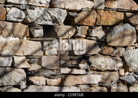 Stone wall constructed from various rock types, showcasing nature's textures and patterns in a rustic setting Stock Photo