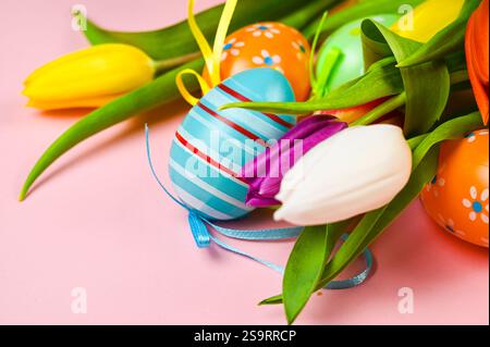Colorful easter eggs and tulips on a pink background. Stock Photo