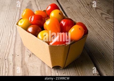 Fresh organic cocktail tomatoes from the market in recyclable cardboard packaging. Stock Photo