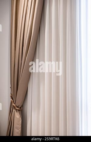 Cozy bedroom interior with light curtains. Close up view of Beige curtain fabric texture and background. Elegant window curtains in a bedroom. Home de Stock Photo
