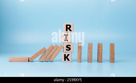 RISK management and domino effect concept, Set by wooden blocks on light blue background, Financial Crisis, Economic, Business risk management concept Stock Photo