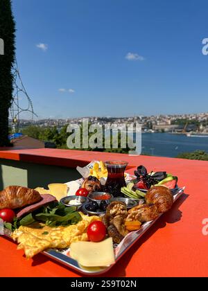This image showcases a colorful Turkish breakfast spread, featuring fresh vegetables, cheeses, omelette, pastries, dried fruits, and a glass of tradit Stock Photo