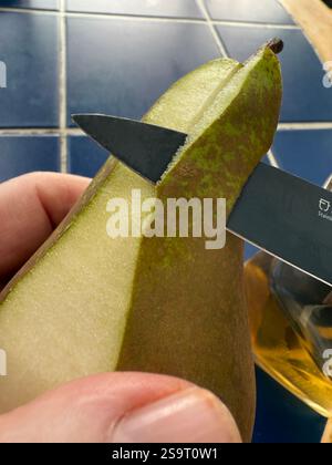 Peeling a conference pear with a knife Stock Photo