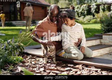 Grandfather and Grandson Playing with a Cat in Backyard Stock Photo