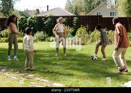 Family Playing Soccer Outdoors in Garden Stock Photo