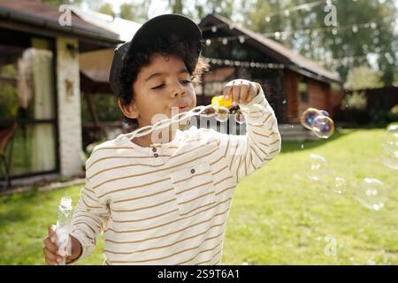 Blowing Soap Bubbles Outdoors in Sunlit Backyard Stock Photo