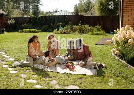 Enjoying Family Picnic Outdoors on Green Lawn Stock Photo