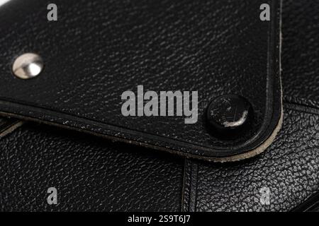 detailed view showcases the texture and design of a black leather accessory. Attention is drawn to the unique stitching and metallic fastening element Stock Photo