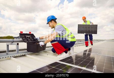 Workers Or Electricians Installing Or Maintaining Solar Panels On Roof Stock Photo