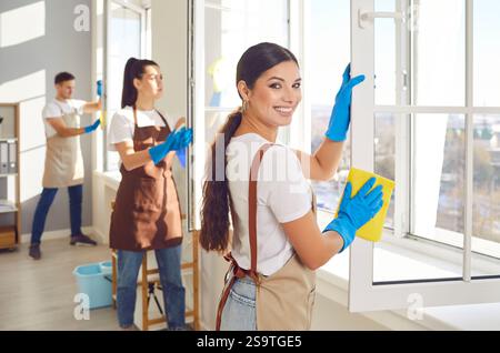 Team of a young janitors cleaning windows in office or at home using household supplies. Stock Photo