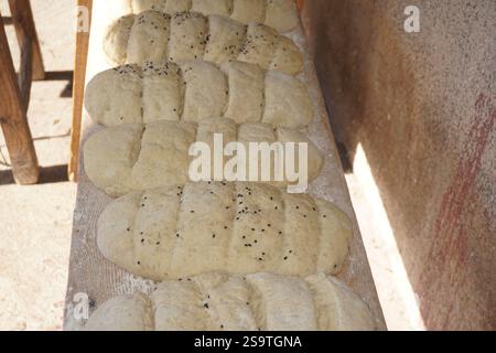 Handmade and homemade sourdough bread loaves sprinkled with white and black sesame seeds carved into slices in a row outdoors ready to be baked Stock Photo