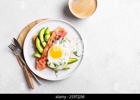 Toasted sandwich with fried egg, bacon, avocado and microgreens and cup of coffee for healthy breakfast or keto lunch on white background, copy space. Stock Photo