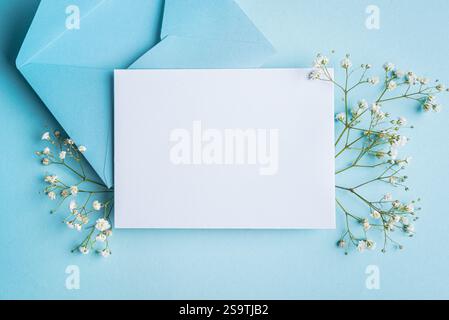Greeting or invitation card mockup, white empty blank  with floral decor on bue background, copy space. Stylish creative mockup with white gypsophila Stock Photo