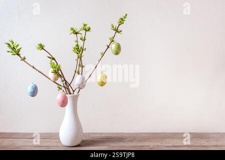 Painted Easter eggs on spring twigs, neutral background, minimal composition. Happy Easter bouquet. Stock Photo