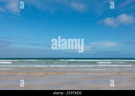 Clear blue skies and gentle waves on a Cornish sandy beach in Porthkidney Beach, Cornwall, England, UK Stock Photo