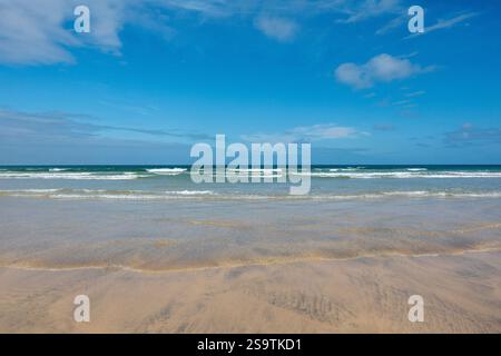 Clear blue skies and gentle waves on a Cornish sandy beach in Porthkidney Beach, Cornwall, England, UK Stock Photo