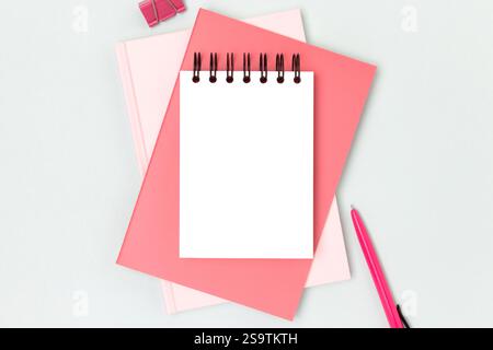 Workspace with clean notepad mock up and pink colored stationery on a blue background. Business concept with copy space. Stock Photo