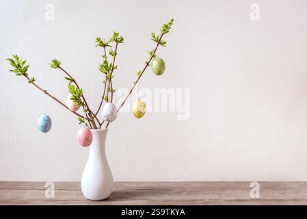 Painted Easter eggs on spring twigs, neutral background, minimal composition. Happy Easter bouquet. Stock Photo