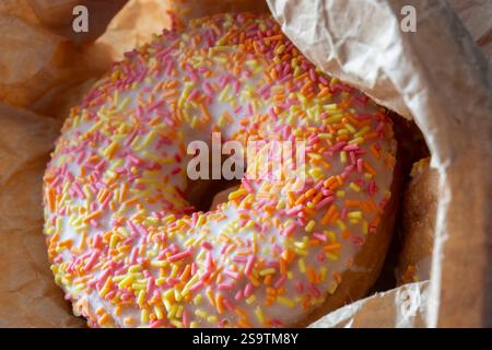 Iced ring doughnuts sprinkled with hundreds and thousands in a brown paper bag. Recycling eco friendly biodegradable packaging Stock Photo
